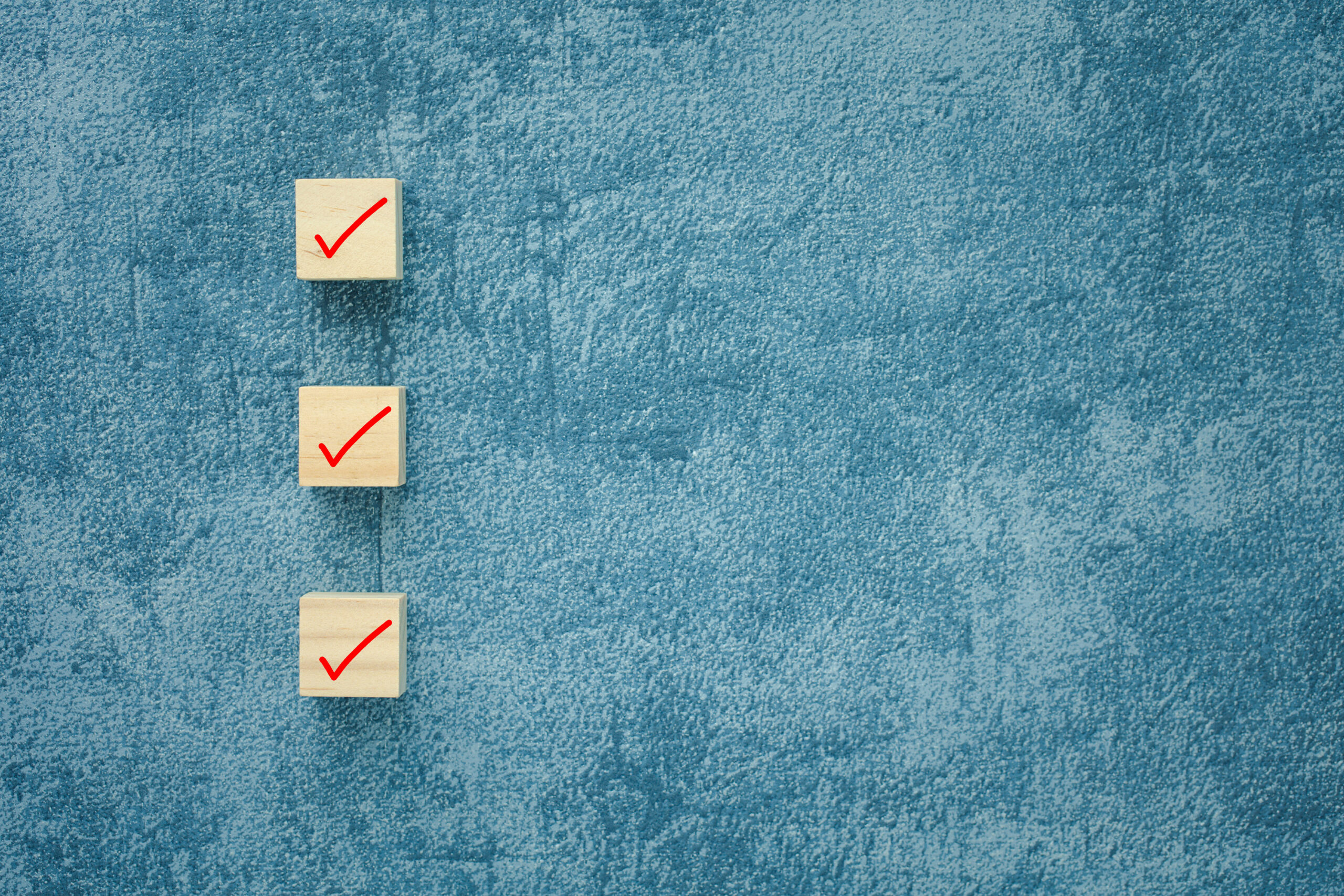 check mark on wooden cubes with blue background, checklist concept with copy space